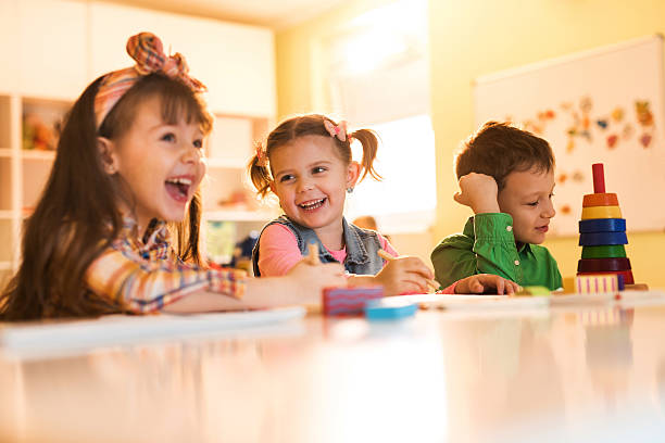 feliz niña pequeña en los jardines de infancia jugando dibujo y divirtiéndose con sus amigos. - student caucasian bonding creativity fotografías e imágenes de stock