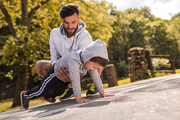 istock Father assisting little boy in doing push-ups in the park. 539673420