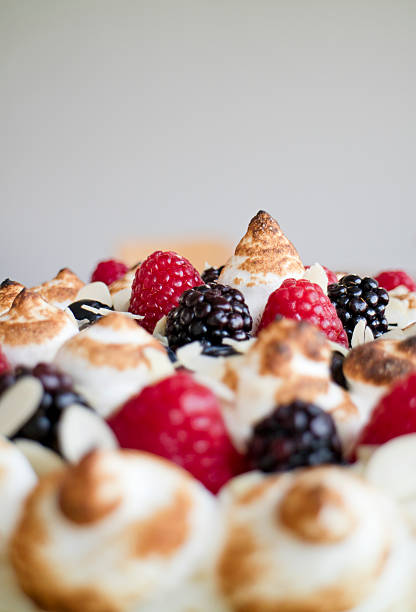 close up of a detail cake with raspberries blackberries sliced almond and meringue