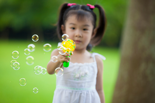 Little girl playing bubbles outdoors