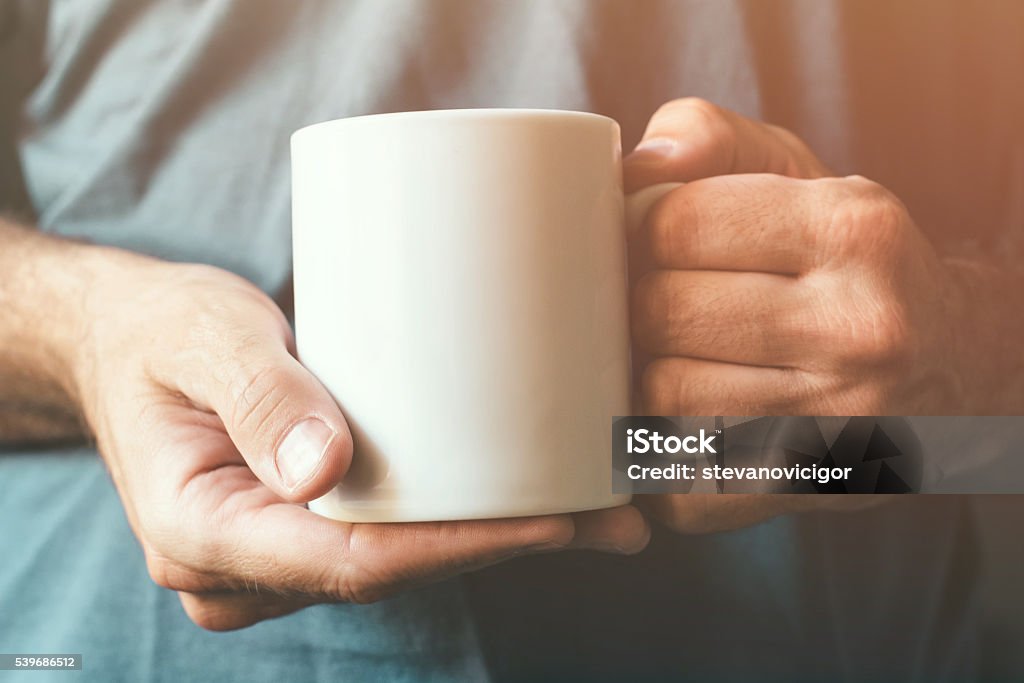 White coffee cup in male hands White coffee cup in male hands, retro toned, selective focus Mug Stock Photo