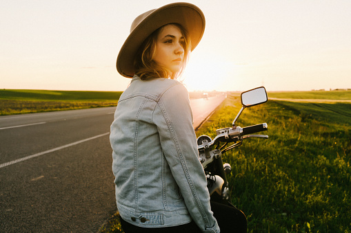 Woman sitting on the motorcycle at sunset 