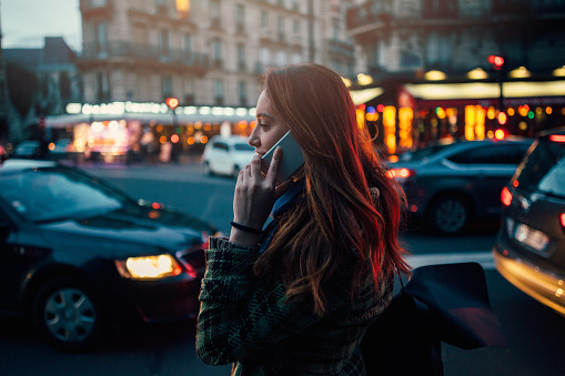 Woman talking on the phone in Paris at night.