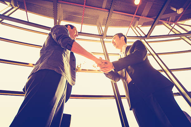 Successful agreement over a profitable business. Two office executives shaking hands over a profitable business agreement. curtseying stock pictures, royalty-free photos & images