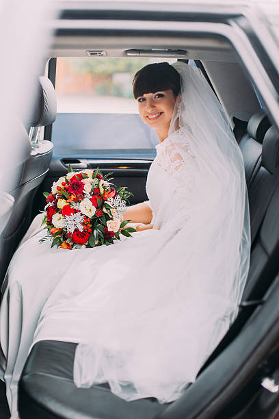 istock Charming young bride with her bridal bouquet in wedding car 539814008