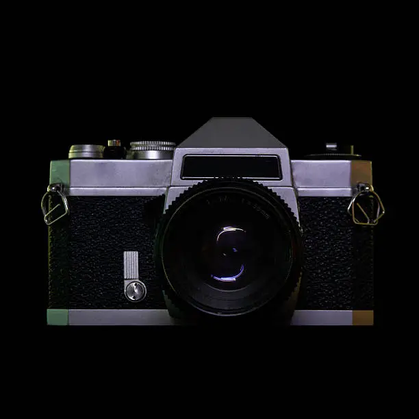 A studio image of a vintage metal analog camera with a 55mm lens on black background