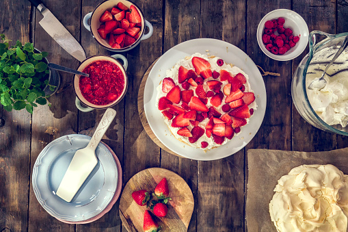 Delicious Berry Pavlova Cake with fresh strawberries, raspberries, mint leaves and whipped cream.