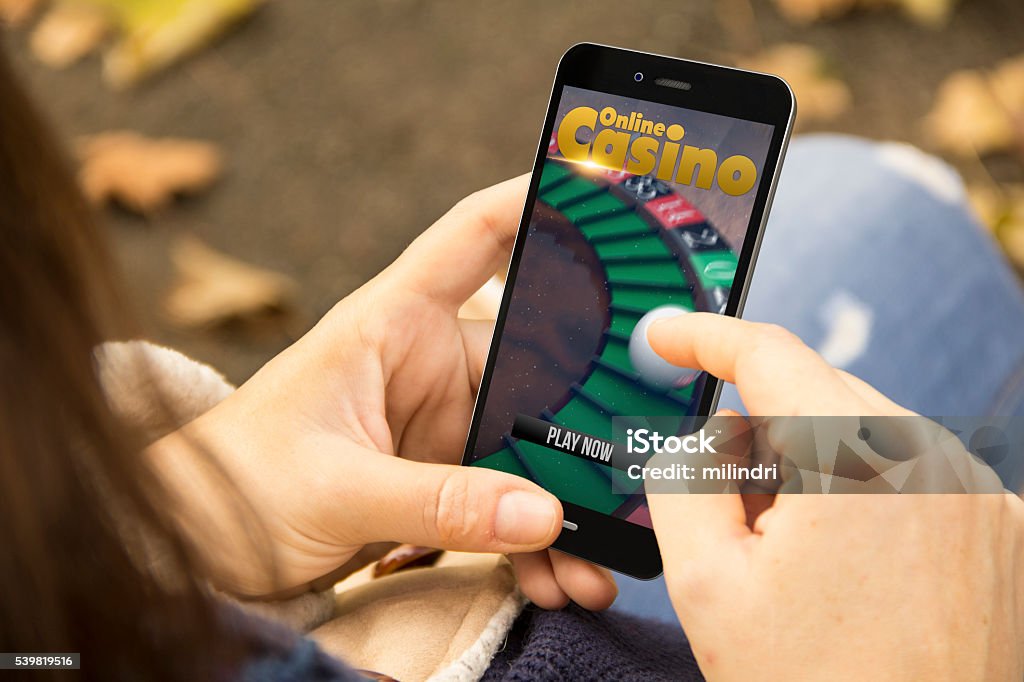 woman with online casino phone in the park addiction concept: woman holding a 3d generated smartphone with online casino website on the screen. Graphics on screen are made up. Casino Stock Photo