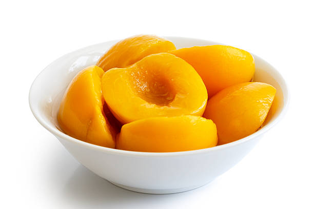 Canned peach halves in bowl isolated on white background. In perspective.