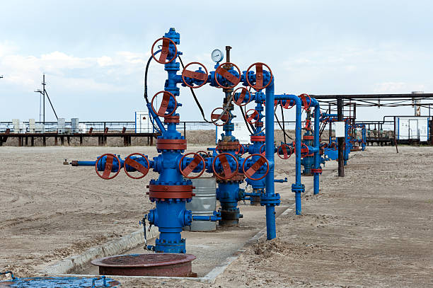 Oilfield. Group production wellheads and conduit with valves. Oil and gas industry. wellhead stock pictures, royalty-free photos & images