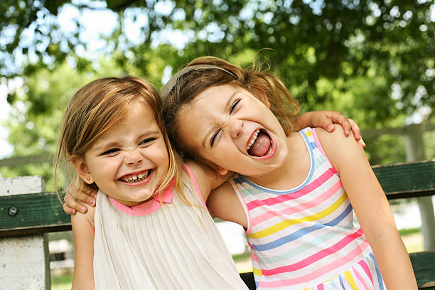 Little sisters hugging outdoor. Cheerful little girl hugging in the park. children laughing stock pictures, royalty-free photos & images