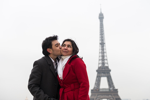 Young man kissing his mother in front of Eiffel Tower