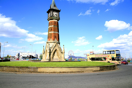 Skegness, Lincolnshire, UK. June 02, 2015. The iconic clock tower landmark with a open top bus and the funfair on the seafront.
