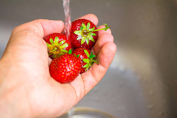 istock Ripe organic strawberry in hand under running water on kitchen 539849364