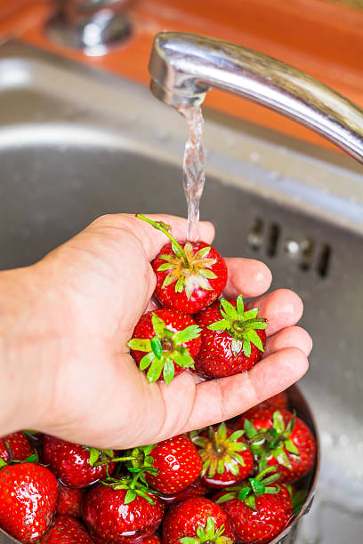 istock Ripe organic strawberry in hand under running water on kitchen 539849404