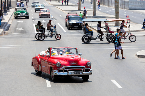 Havana, Сuba - April 13, 2016: Red vintage American car with tourists driving through the streets in Havana Vieja, Cuba, 50 megapixel image.