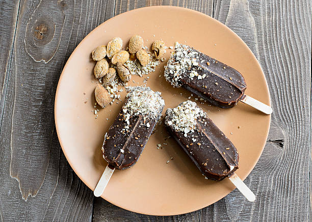 istock Chocolate popsicles with nuts on a brown wood background 539853262