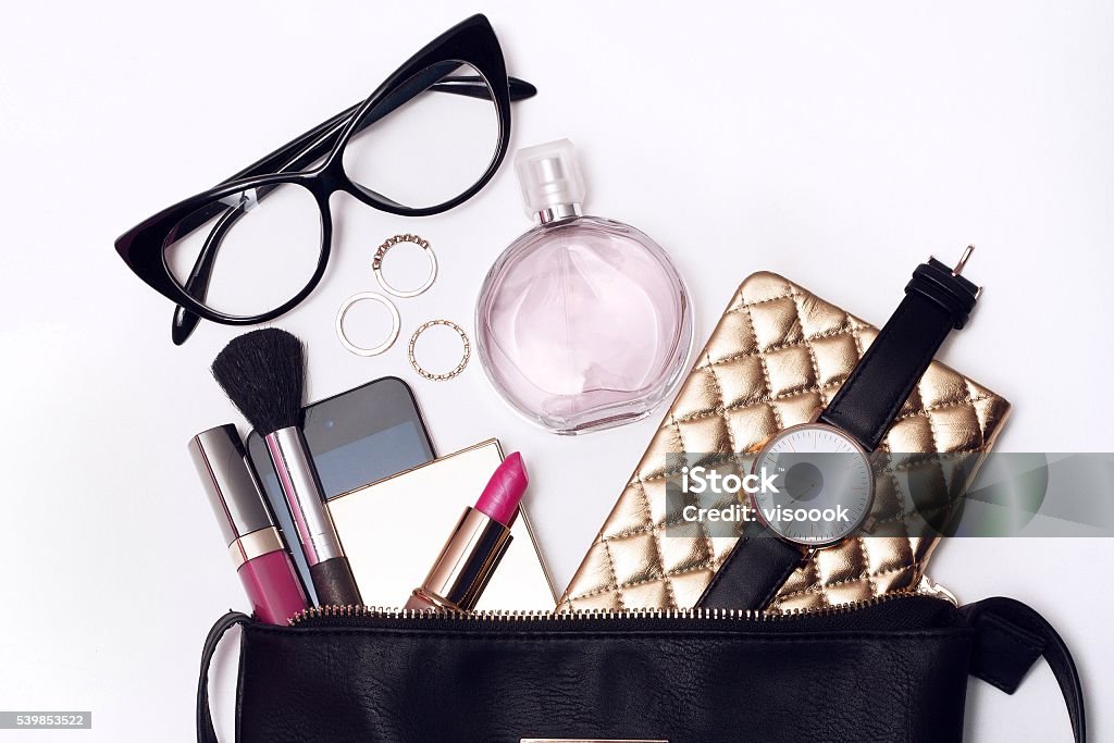 Fashionable female accessories watch glasses perfume Fashionable female accessories watch glasses lipstick perfume and black purse. Overhead of essentials for modern young woman. Above Stock Photo