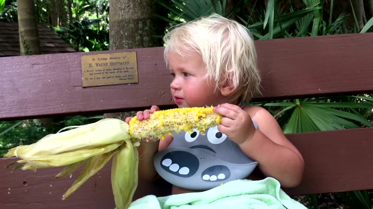 Boy eating corn on a bench