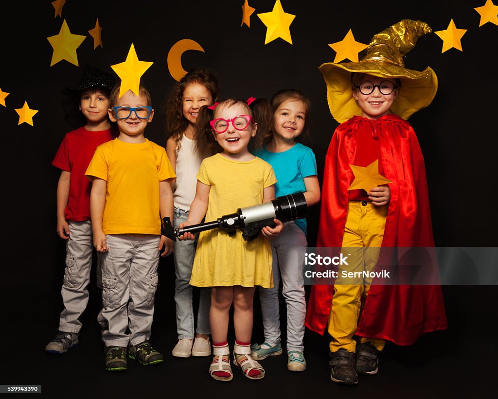 Six kids in stargazers costumes with telescope Group of six boys and girls in stargazers costumes watching handmade stars and moon against black background Child Stock Photo