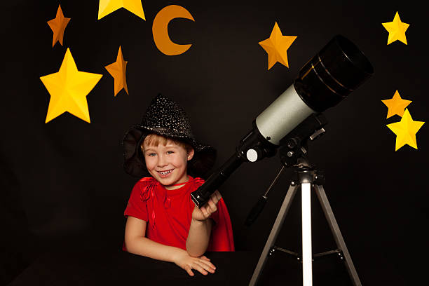 istock Happy boy with a telescope on black background 539945394