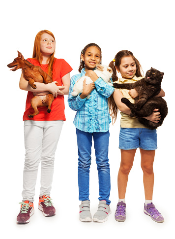 Three diverse girls standing holding their beloved pets cat, rabbit and dog