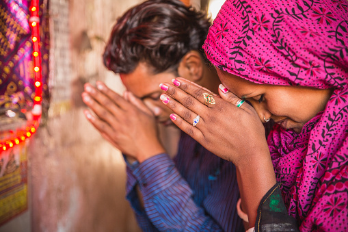 Beautiful young Hindu couple during Puja, on a Jaipur street. They are praying in front of an altar. Many of those little altars can be seen, on the sidewalks, throughout India.