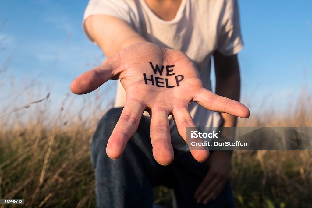 We help - helping hand hand reaching out in order to help Refugee Stock Photo