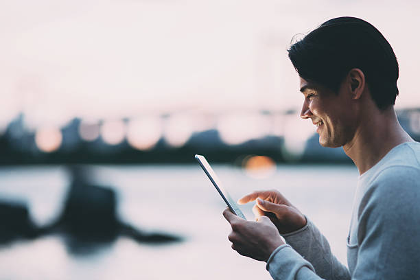 Young japanese man texting on the tablet