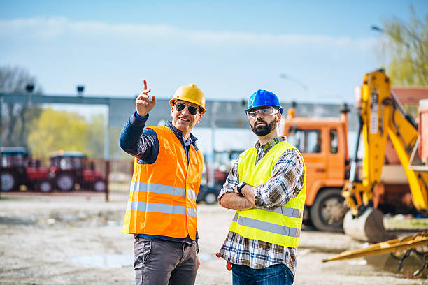 istock Two engineers posing near trucks and machinery on construction site 539954786