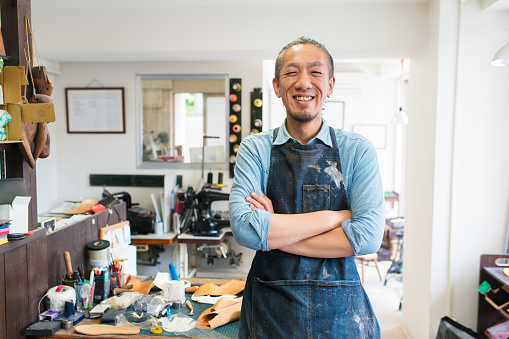 Portrait of a craftsman wearing an apron looking into the camera smiling. Kyoto, Japan. May 2016