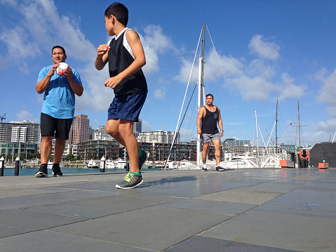 New Zealanders of polynesian ethnicity playing touch rugby in an urban setting. The focus is on the young pasifica boy.