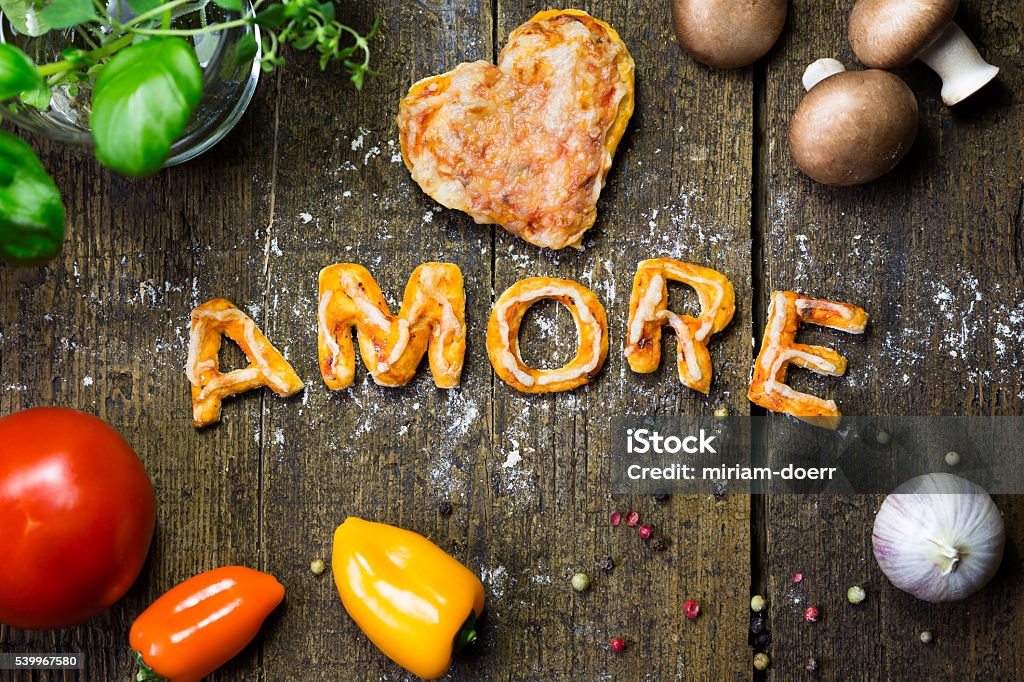 dough letters and vegetables on rustic wooden table with flour, dough letters and vegetables on rustic wooden table with flour, italian word amore, which means love Basil Stock Photo