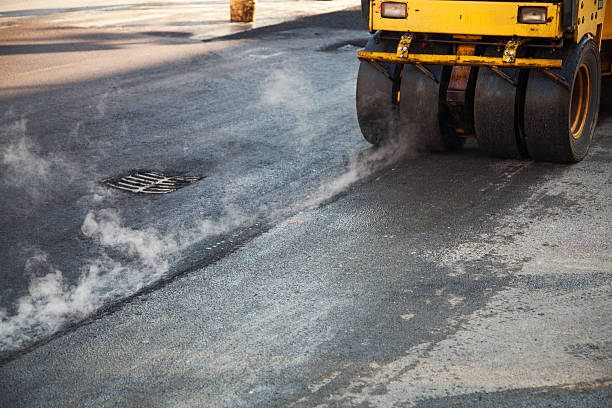 Road repairs, new layer of asphalt Yellow steamroller pressing the new asphalt surface to level it. compactor photos stock pictures, royalty-free photos & images