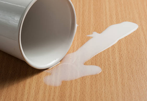 istock Milk spilled from glass on wooden 539971332