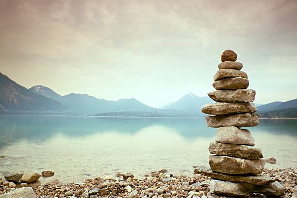 istock Balanced stone pyramide on shore, blue water of mountain lake. 539972686