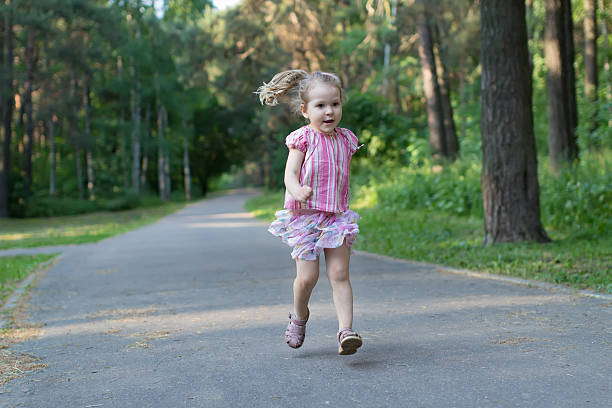 istock Blonde three years old girl running on asphalt park footpath 539977220
