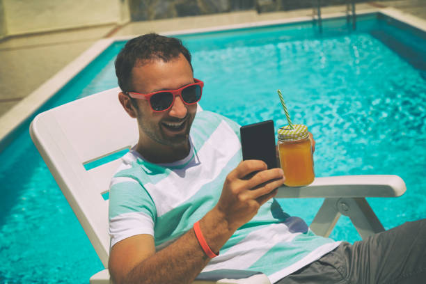 istock Young man on the swimming pool with cellphone. 539978028
