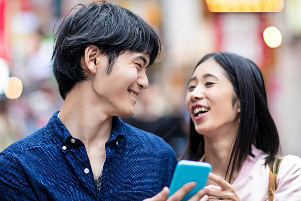 istock Young Japanese couple laughing watching a mobile phone message 539980954