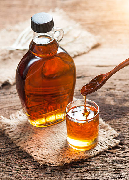 maple syrup in glass bottle on wooden table maple syrup in glass bottle on wooden table maple syrup stock pictures, royalty-free photos & images