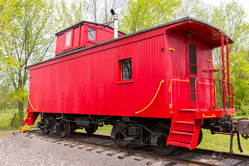 An old red wooden railroad caboose on track.