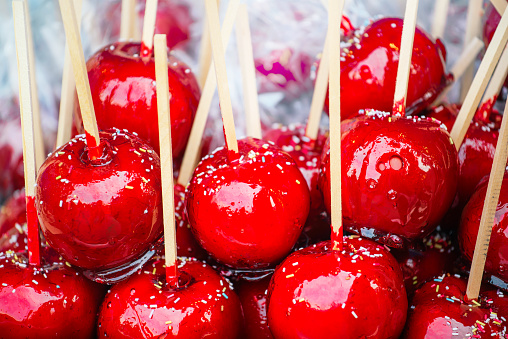 Sweet glazed red toffee candy apples on sticks for sale on farmer market or country fair.