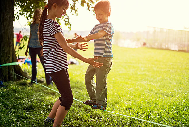 garoto tentando caminhada sobre slackline - pre adolescent child little girls friendship child - fotografias e filmes do acervo