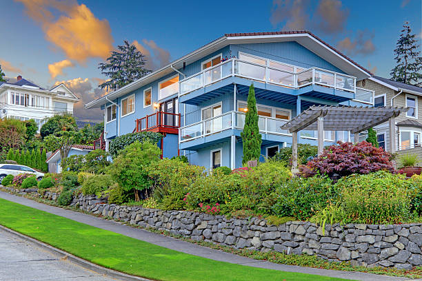 istock Large blue house with summer landscape and rock wall. 539989994
