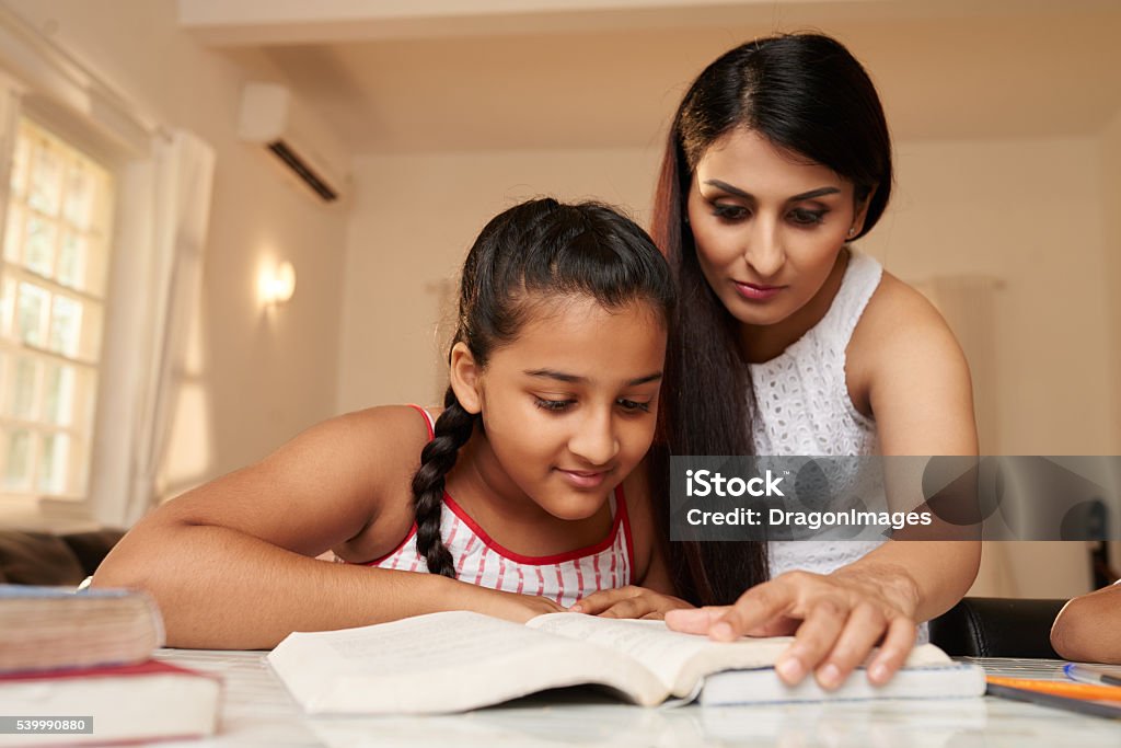 Reading a book Girl reading a book with her teacher at home Homework Stock Photo