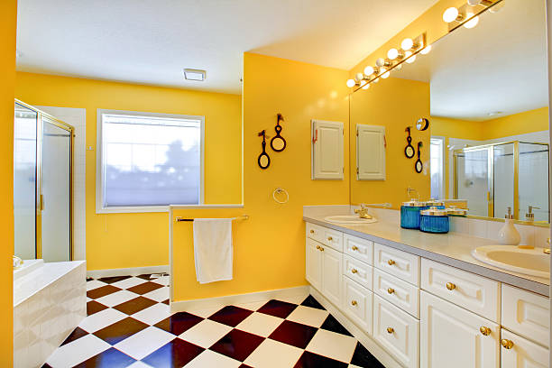 Bright yellow bathroom interior with white cabinets, tile.