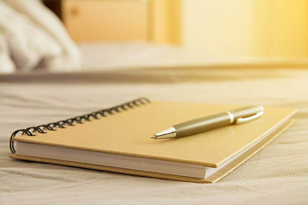 pen on notebook with sunlight in morning stock photo