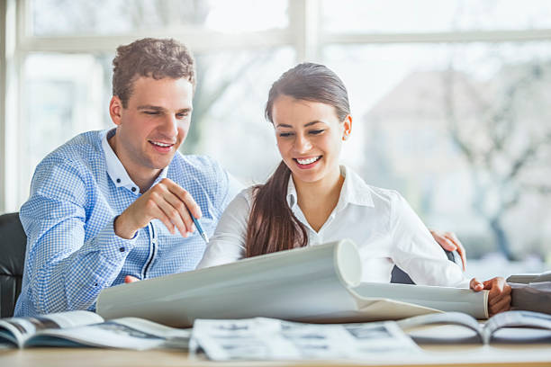 istock Young architects discussing over blueprint at office desk 540089534