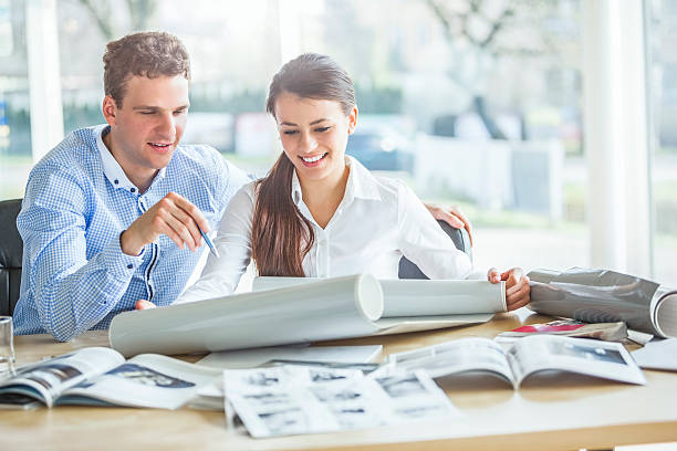 istock Young architects discussing over blueprint at desk in office 540089780