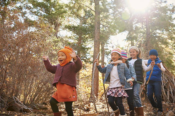 Five young children playing together in a forest,